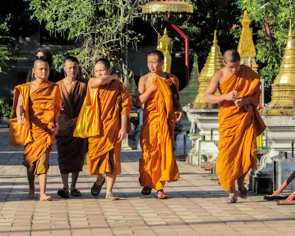 group of people in orange robe standing on gray concrete floor during daytime