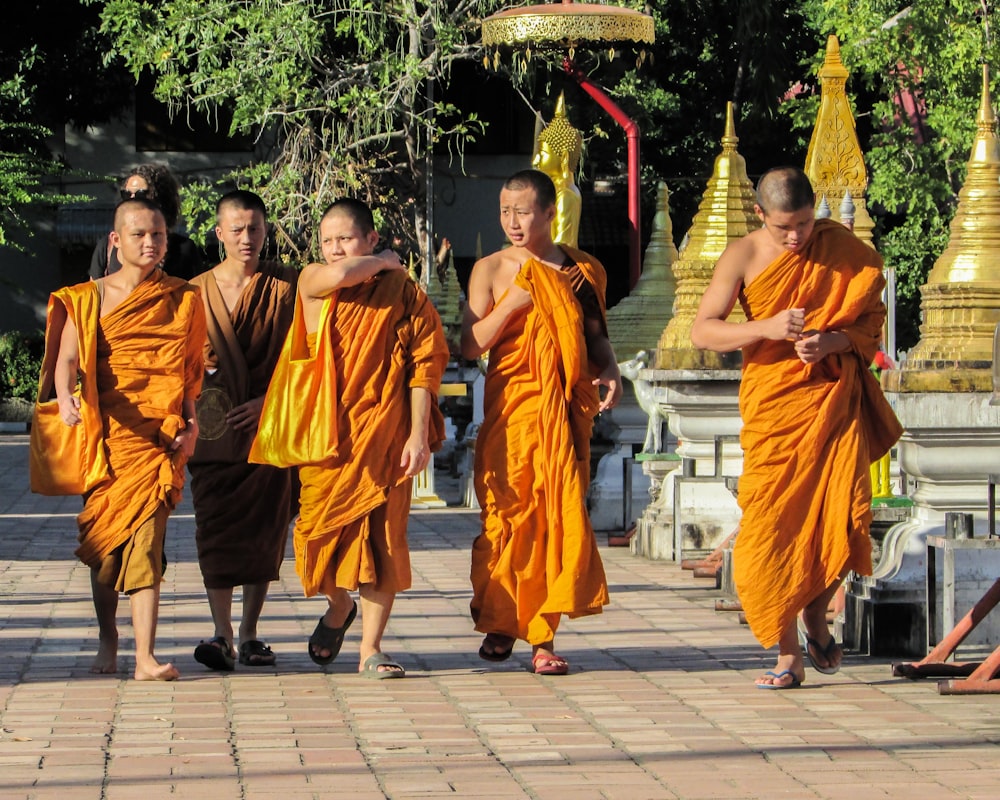 group of people in orange robe standing on gray concrete floor during daytime