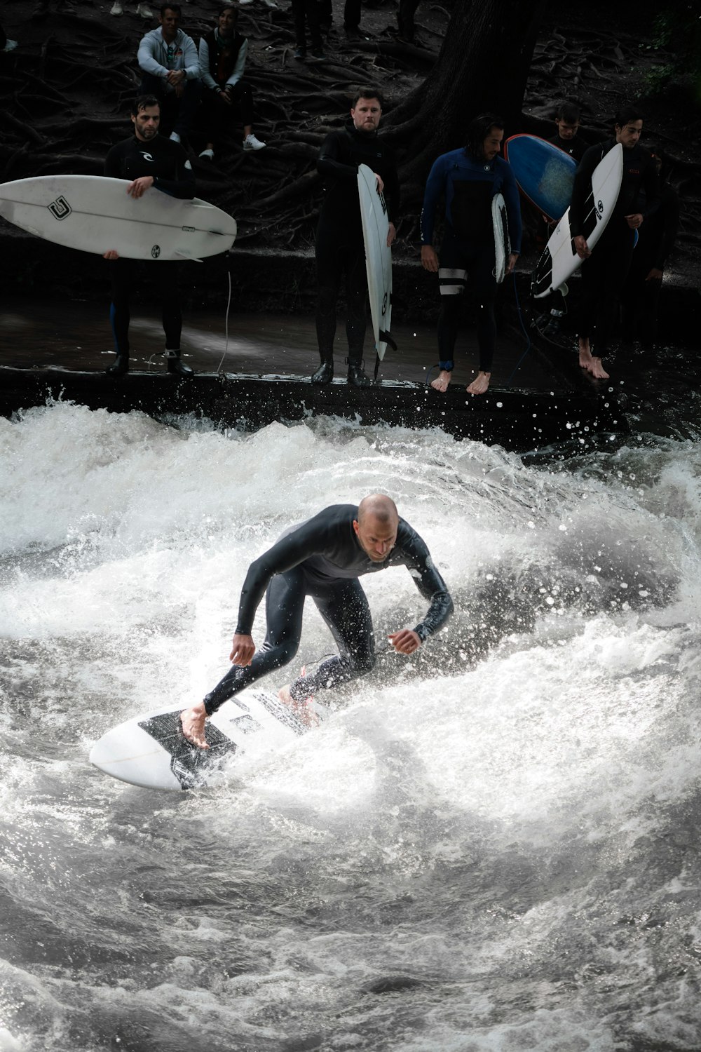 man in blue wet suit riding white surfboard on water during daytime