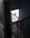 A dimly lit industrial stairwell with a metal mesh railing is partially illuminated by a glowing rectangular sign. The sign has a minimalist design featuring a circle with an orbit-like line and the words 'START BASE NONOS STORY INSPIRA' in a contemporary font.