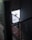 A dimly lit industrial stairwell with a metal mesh railing is partially illuminated by a glowing rectangular sign. The sign has a minimalist design featuring a circle with an orbit-like line and the words 'START BASE NONOS STORY INSPIRA' in a contemporary font.