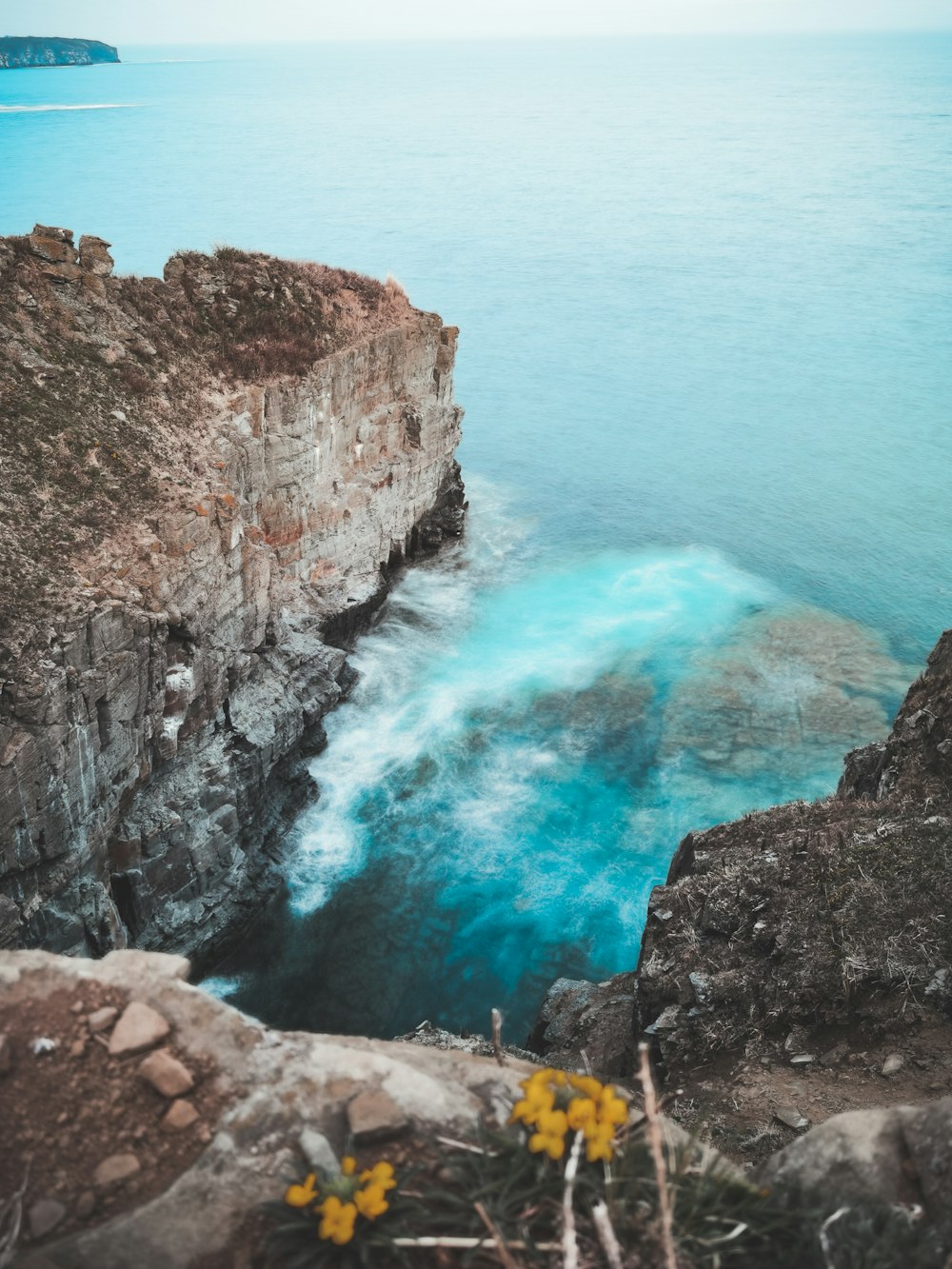 brown rocky mountain beside blue sea during daytime