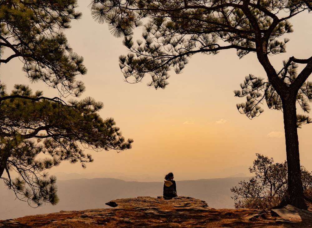 person sitting on brown rock formation during daytime