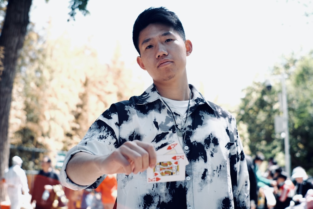 a man in a tie dye shirt holding a card