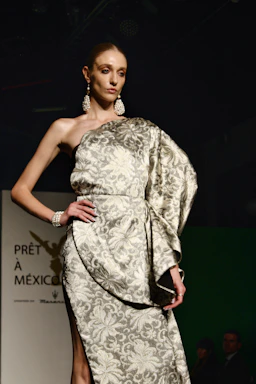 Elegant model wearing a sleek, custom-tailored black gown with intricate beadwork, posing against a Hollywood backdrop.