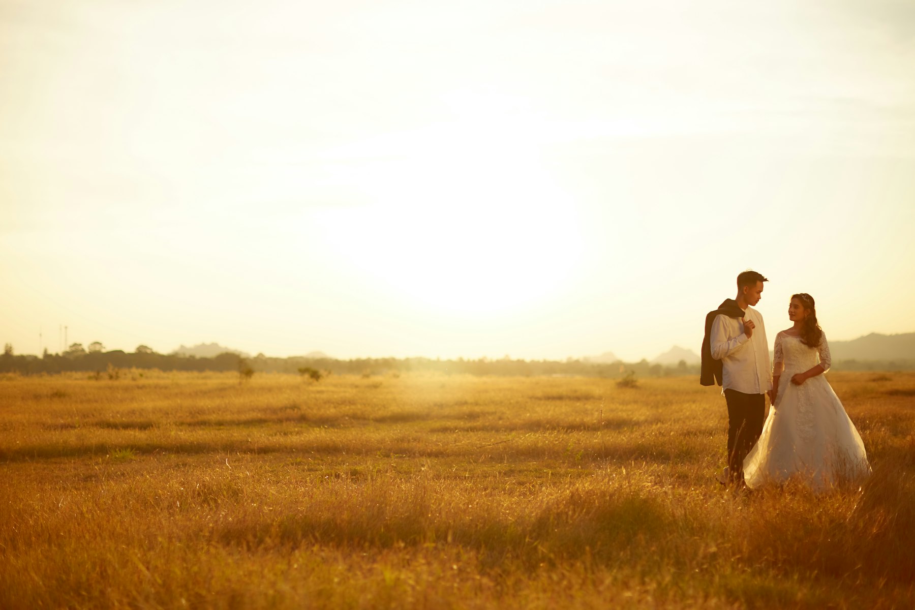 Couple walking through grass at dusk