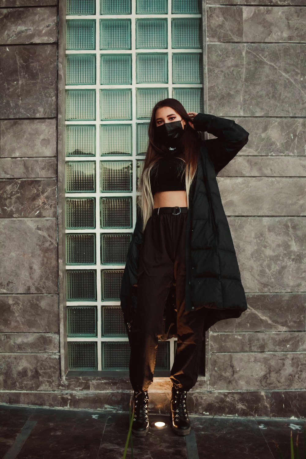 woman in black long sleeve shirt and black skirt standing beside gray concrete wall during daytime