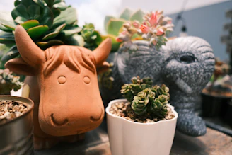 A colorful ceramic cartoon dinosaur planter holding a small fern.