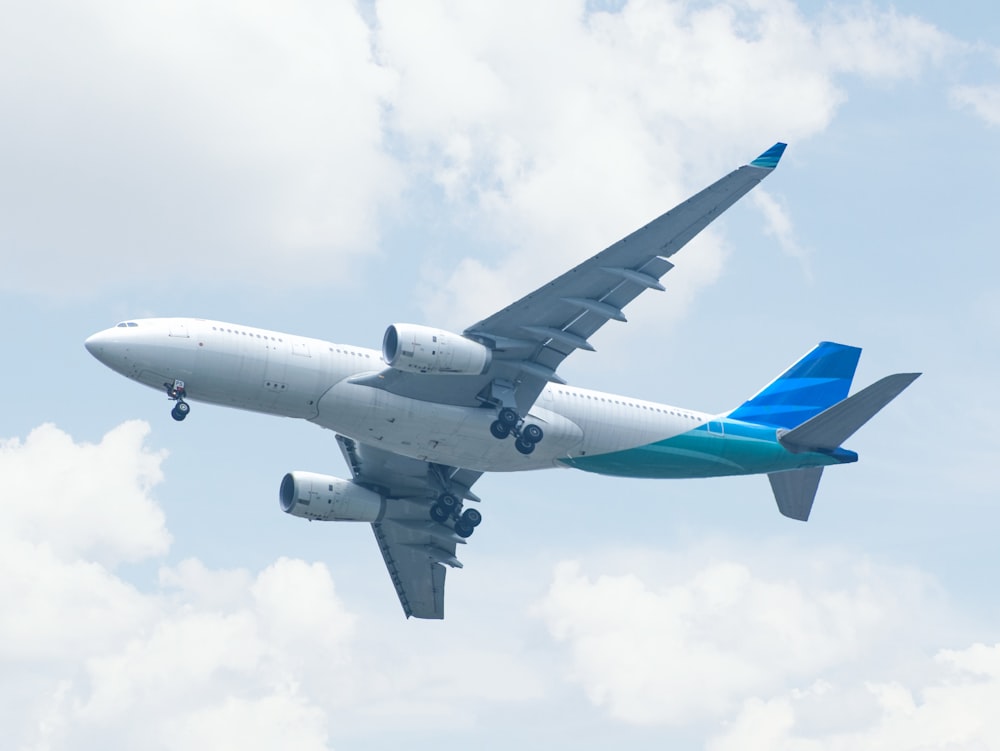 white and blue airplane under white clouds during daytime