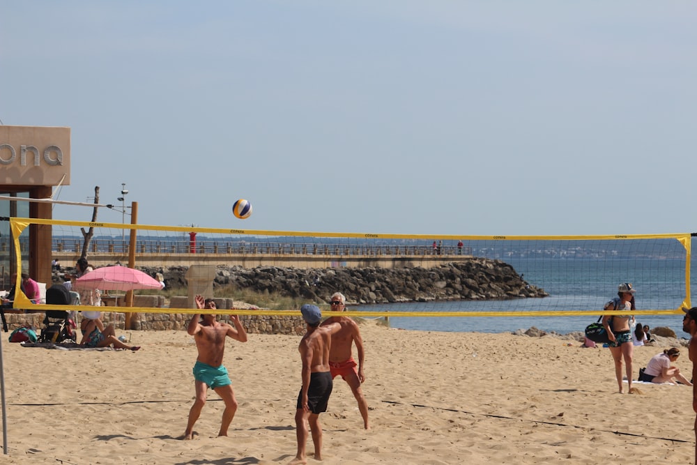 people playing beach volleyball on beach during daytime