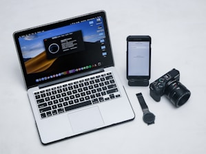 macbook pro beside black iphone 4 and black dslr camera