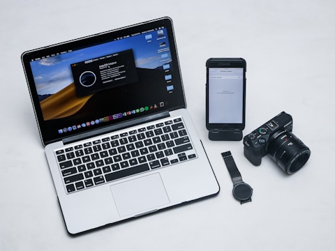 macbook pro beside black iphone 4 and black dslr camera