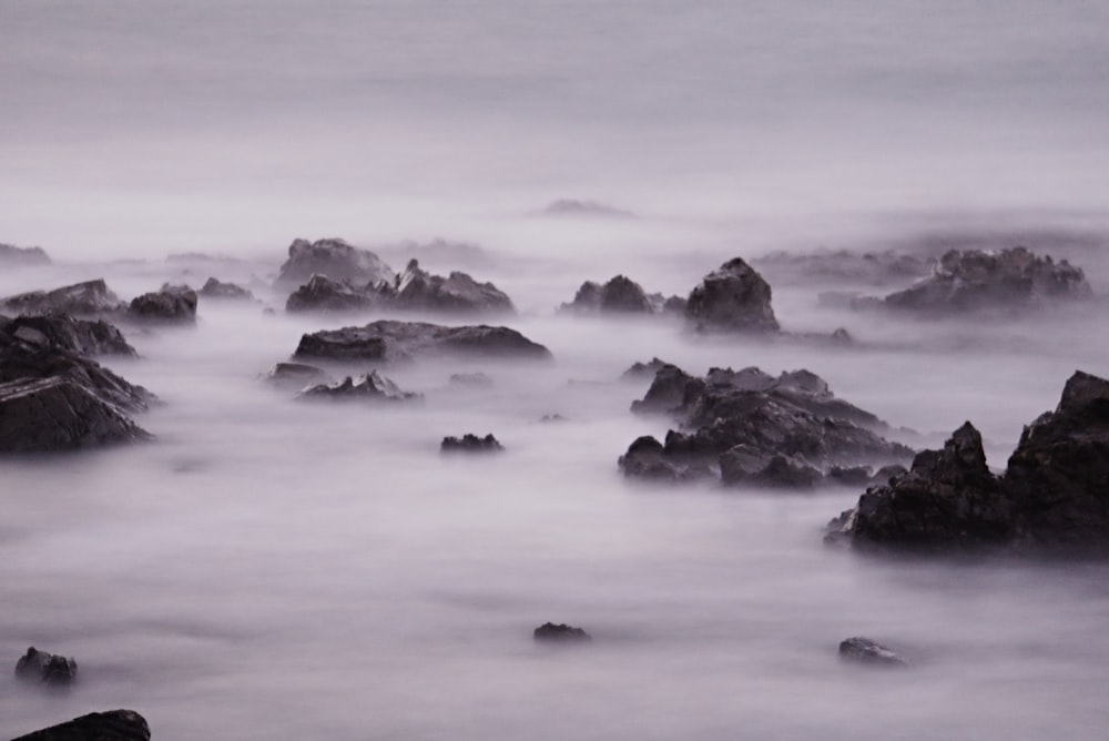 grayscale photo of rock formation on body of water