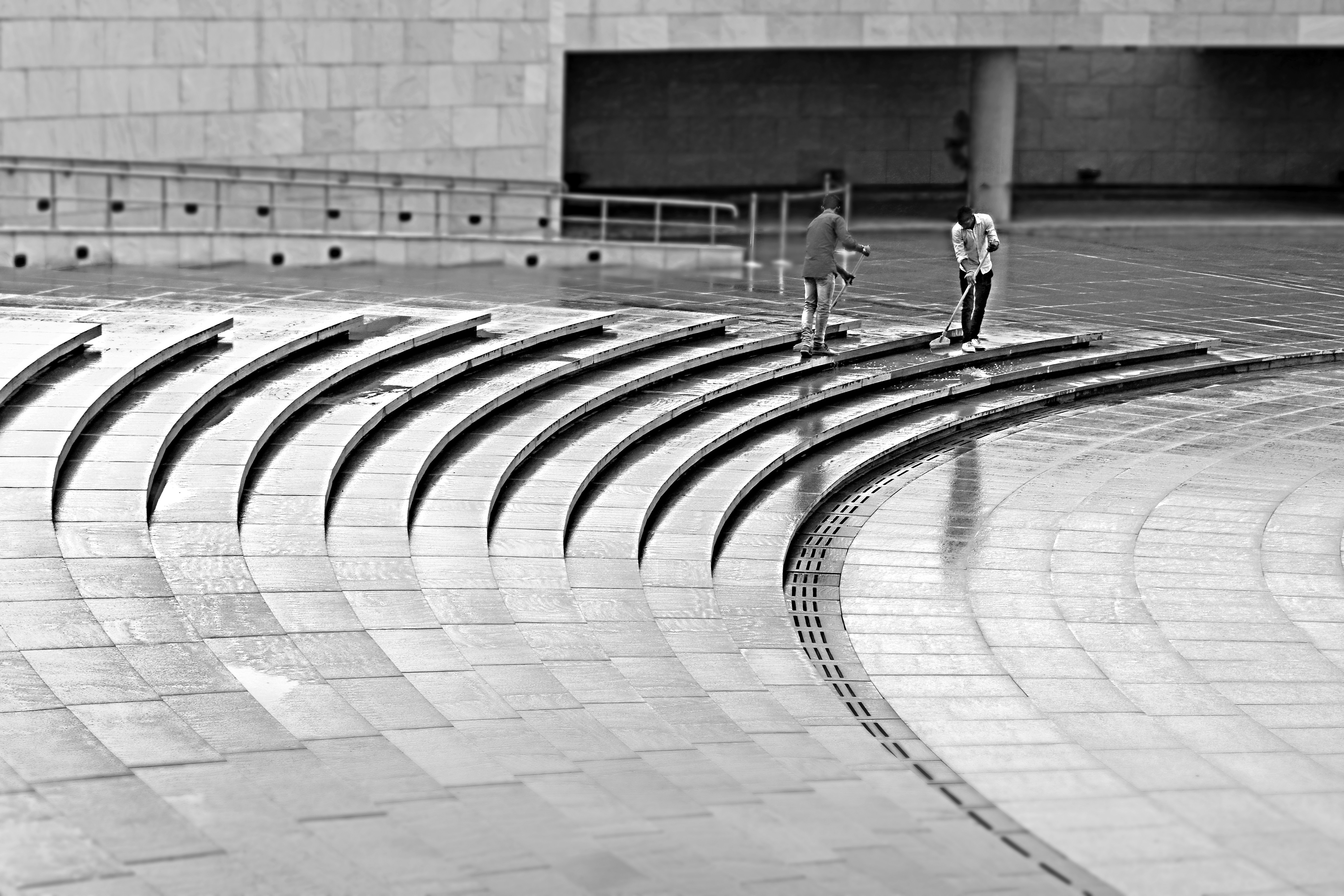 Cleaners cleaning the rain-drenched curved steps of the amphitheater at National War Memorial, India Gate, New Delhi, India