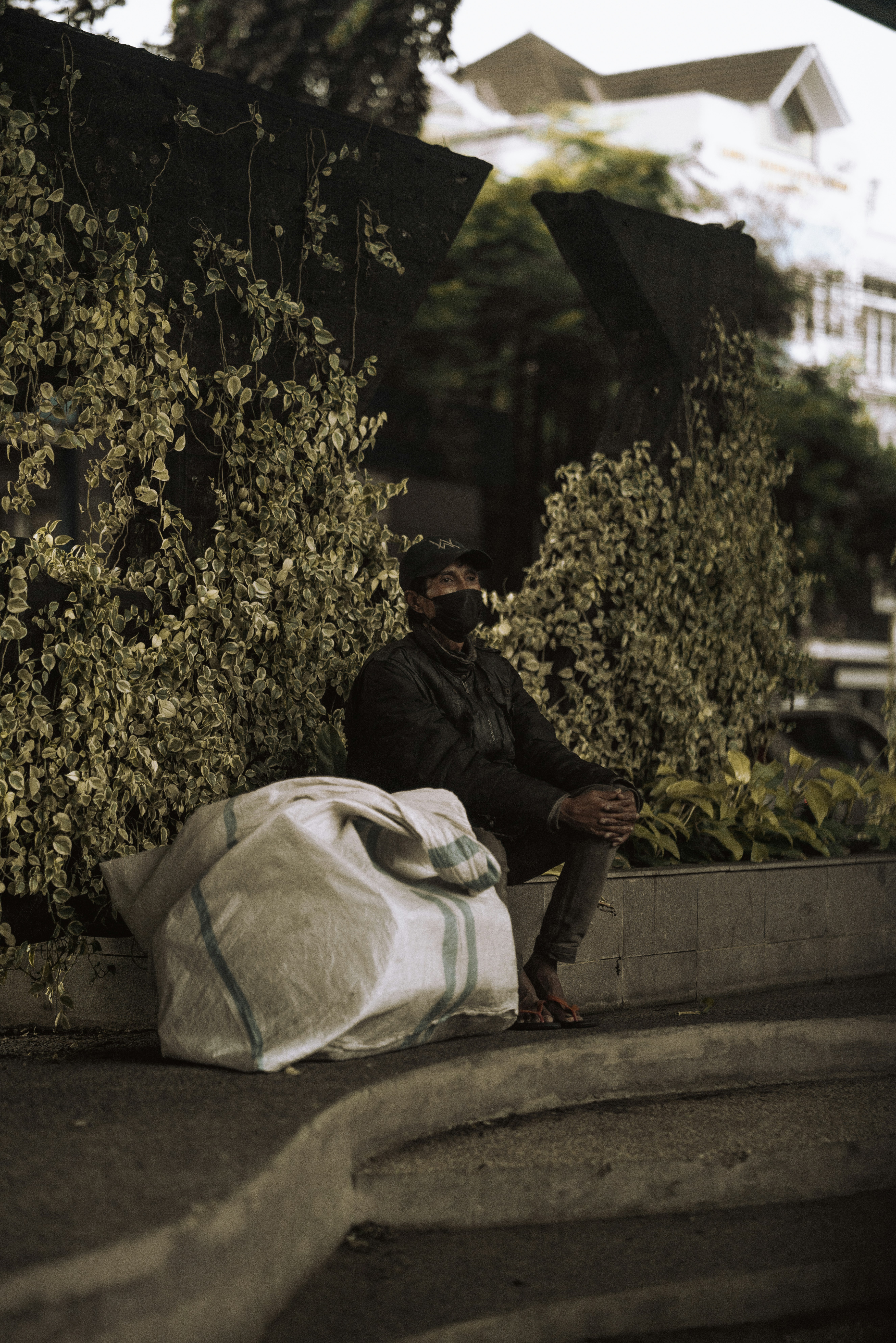 Pria berjaket hitam duduk di bangku beton