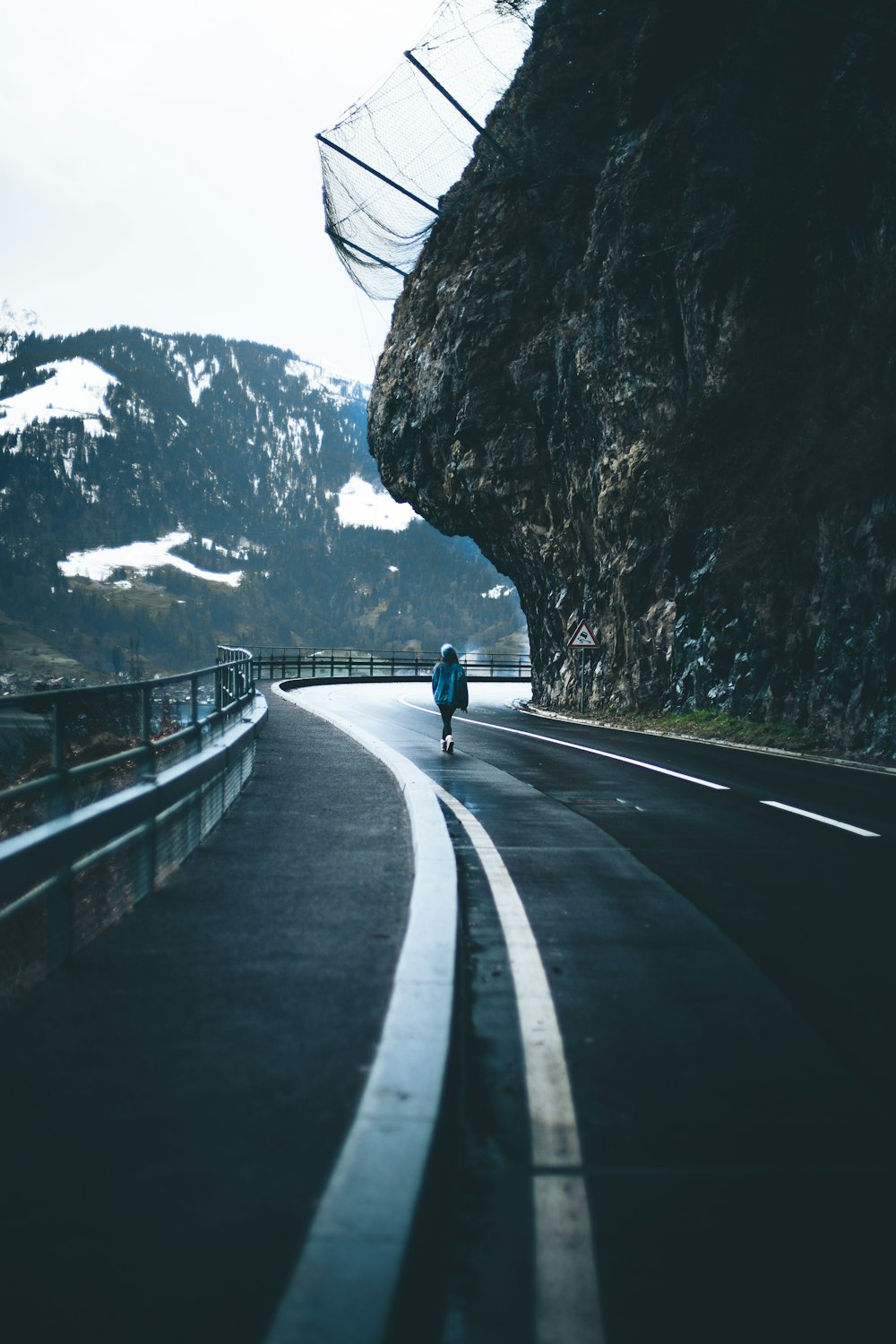 person in blue jacket and black pants walking on gray concrete road during daytime