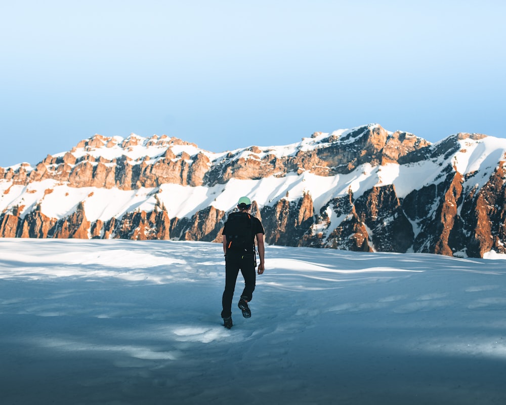 person in black jacket and pants standing on snow covered ground during daytime