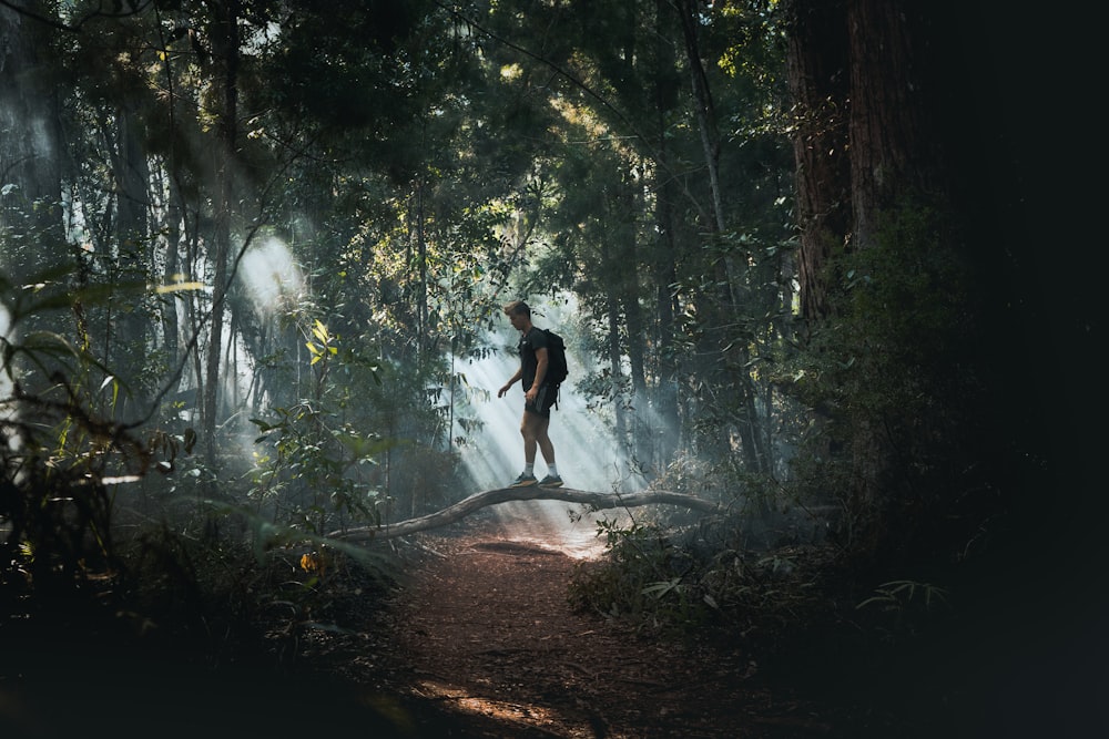 homem de camisa preta e calção preto andando na floresta durante o dia