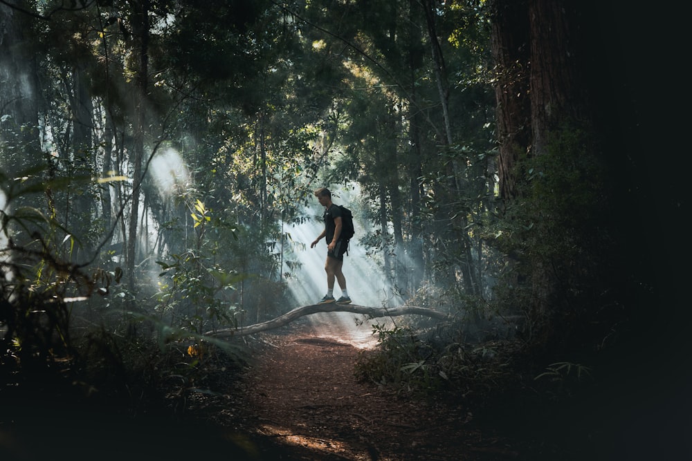 man in black shirt and black shorts walking on forest during daytime