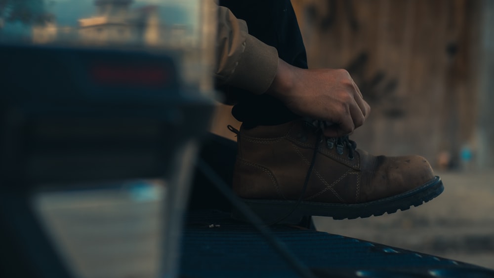 person in brown leather work boot