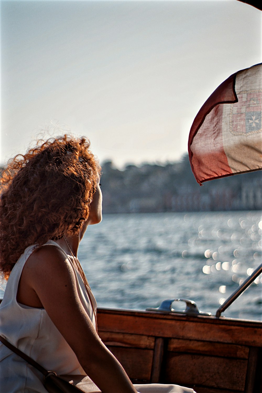 woman in white tank top sitting on brown wooden boat during daytime