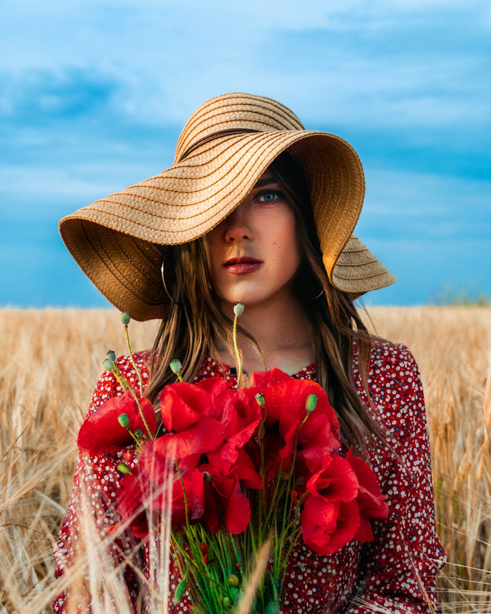 Frau mit braunem Strohhut mit roten Blumen