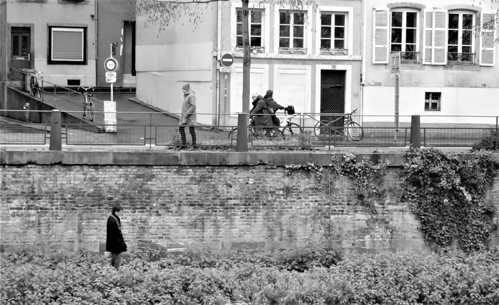 grayscale photo of man walking on sidewalk