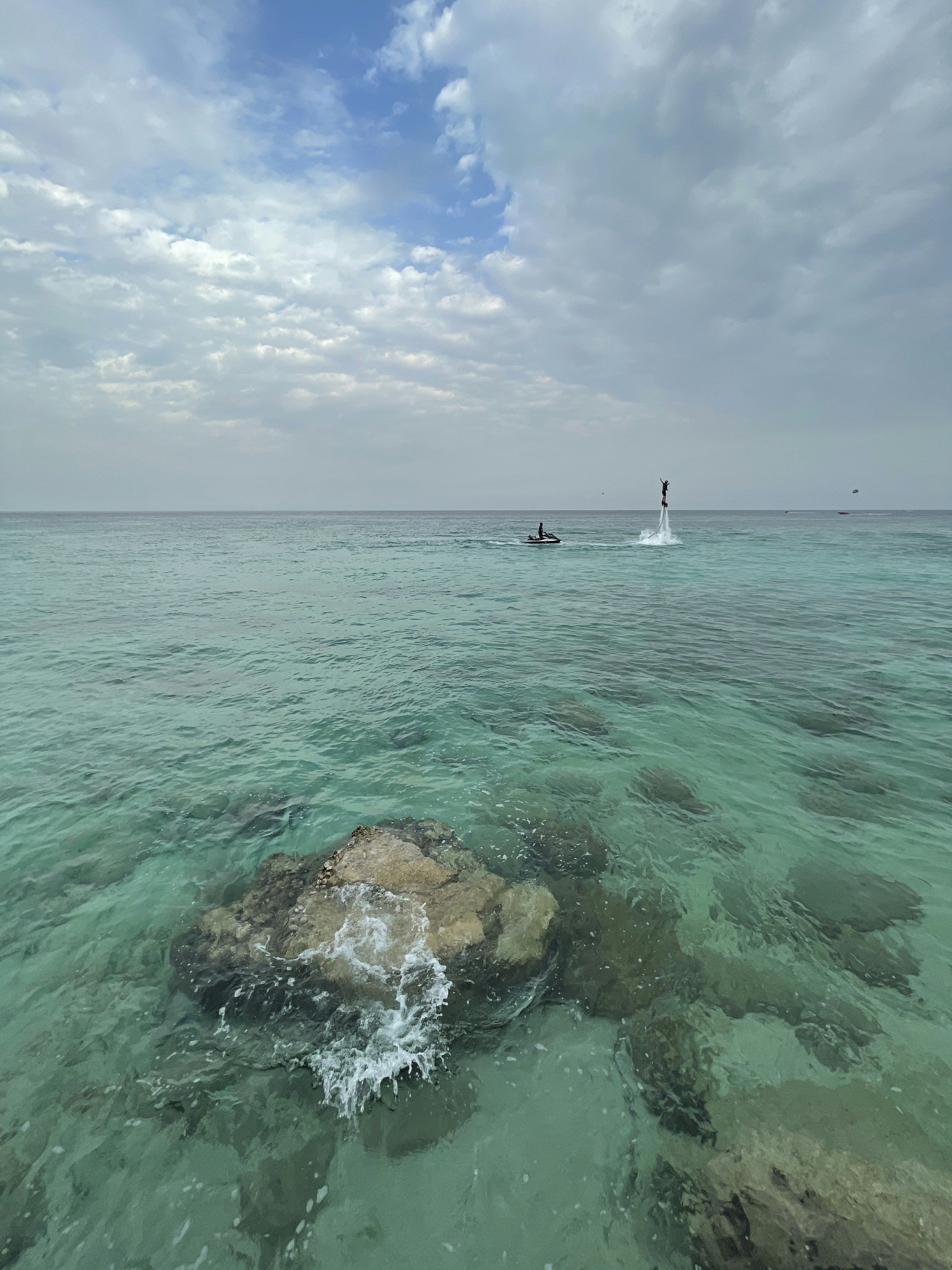 Person flying on flyboard above crystal clear Dubai waters with instructor nearby