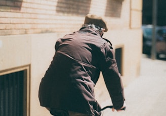 man in black jacket riding bicycle on street during daytime