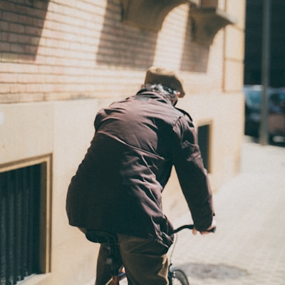 man in black jacket riding bicycle on street during daytime