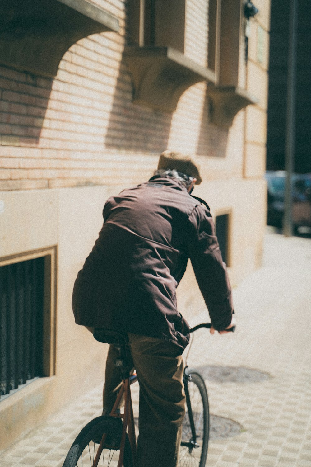 昼間、路上で自転車に乗る黒いジャケットを着た男性