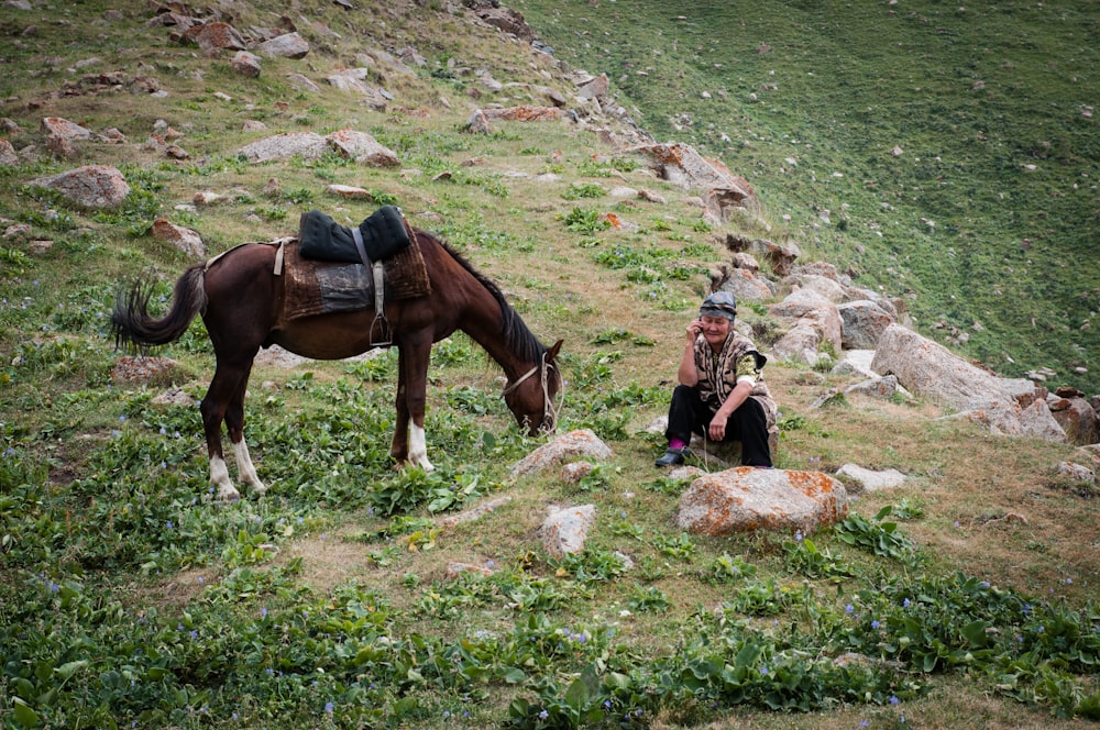 woman in black jacket sitting beside brown horse during daytime