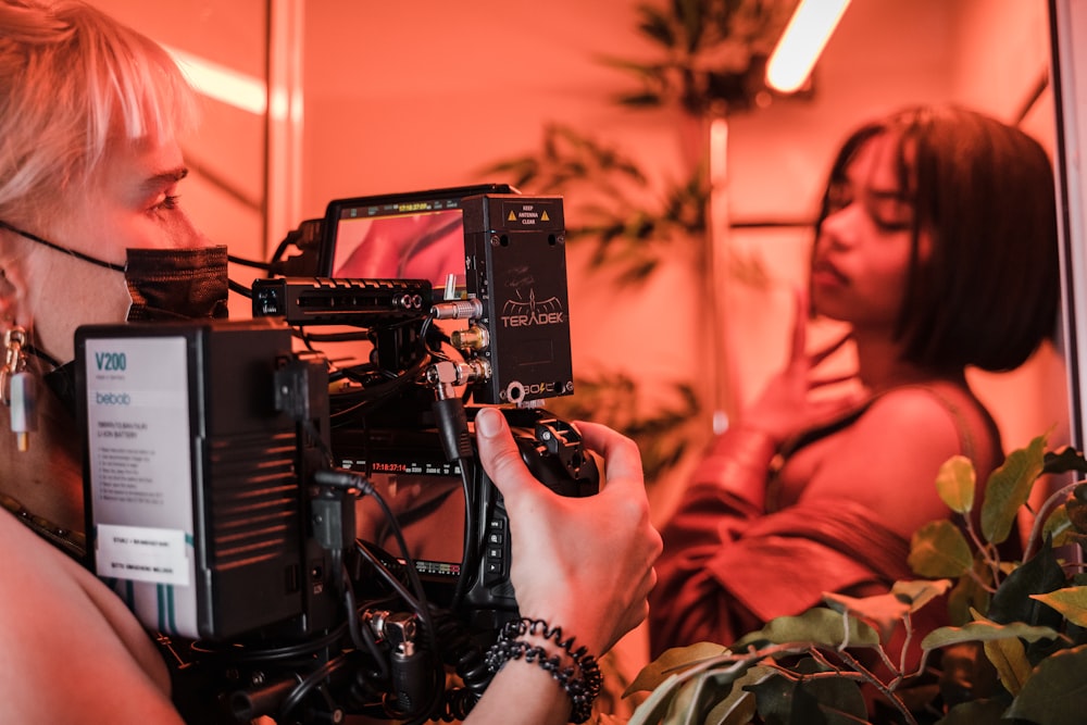 woman in orange long sleeve shirt holding black video camera