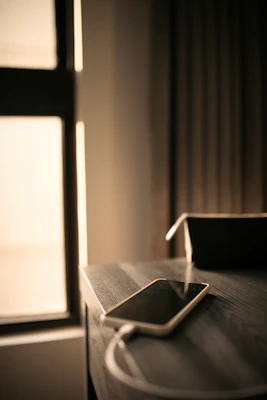 A sleek mobile charger plugged into a smartphone, glowing softly on a wooden desk.