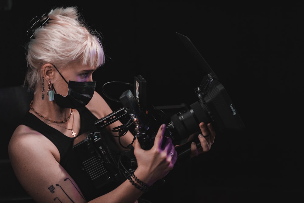 woman in black tank top holding black dslr camera