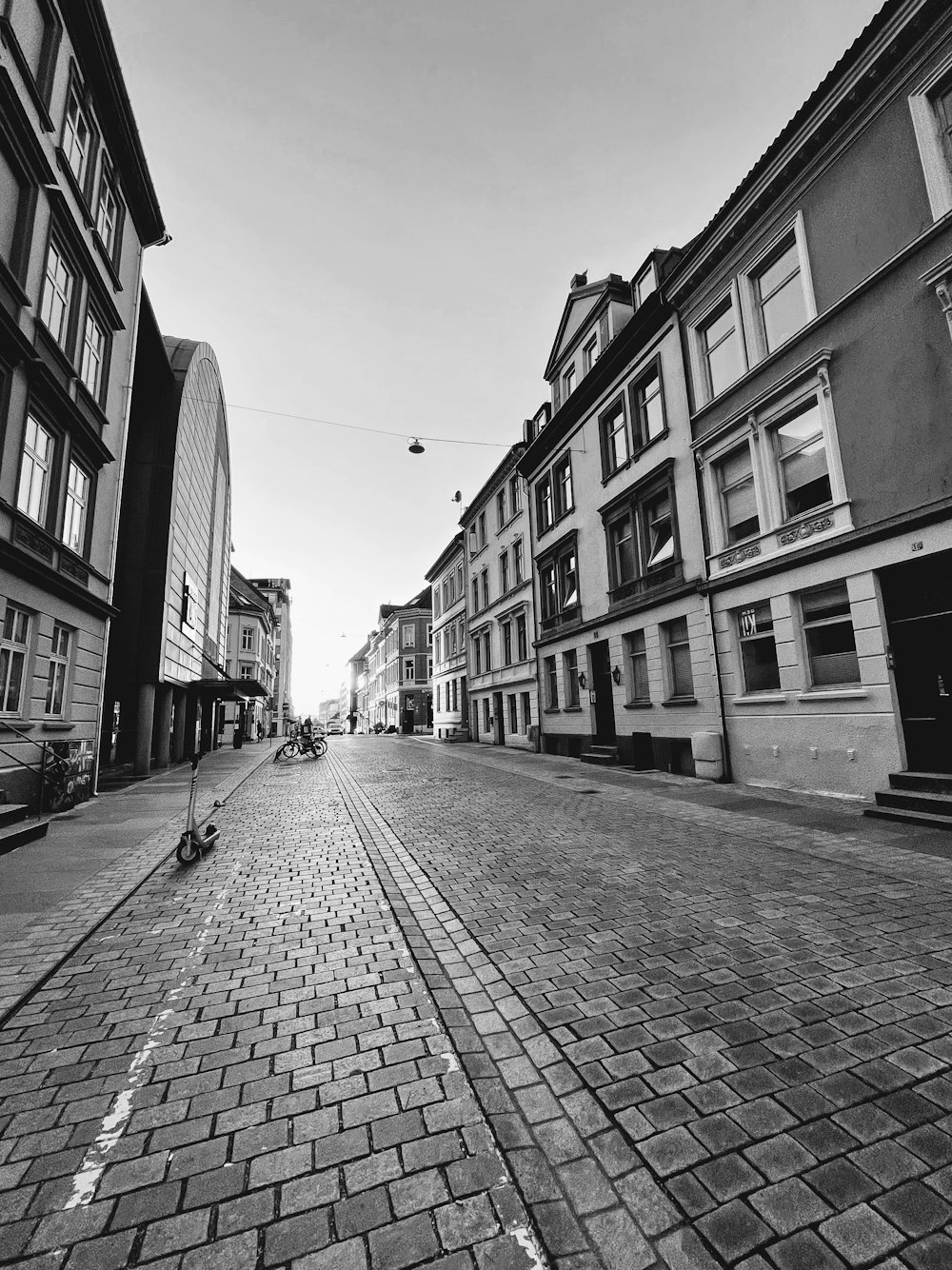 grayscale photo of people walking on street between buildings