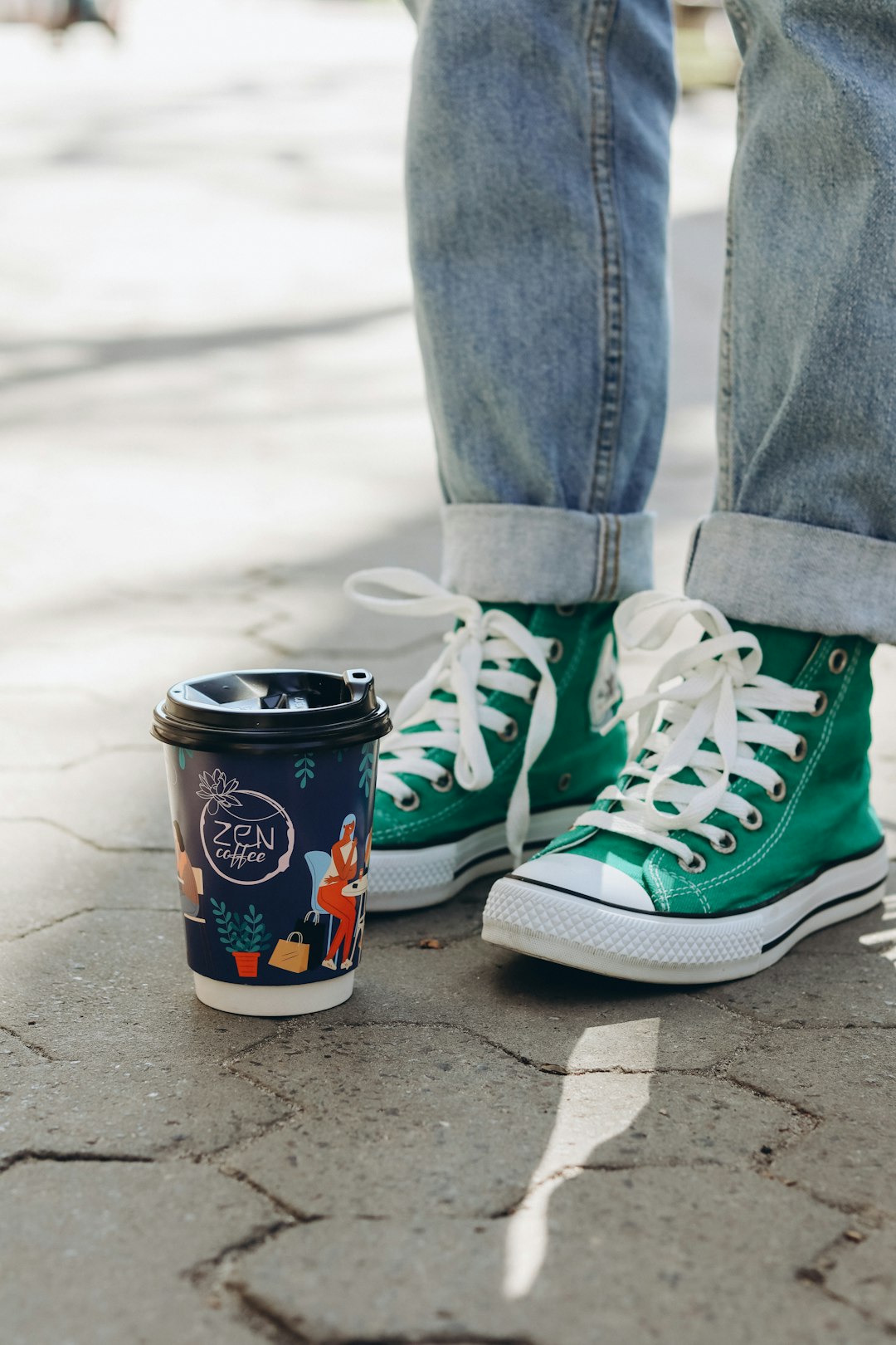blue and white labeled cup beside person wearing green and white nike sneakers