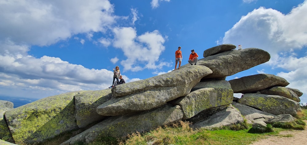 2 men standing on rock formation under blue sky during daytime