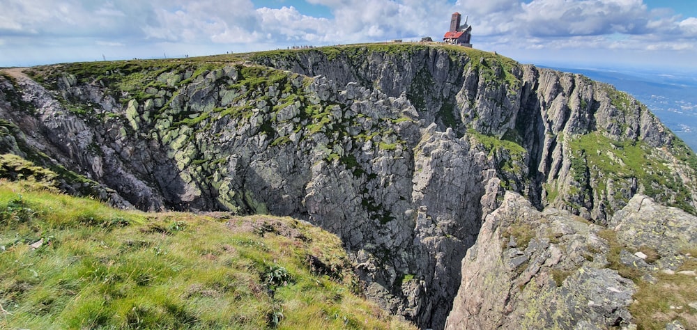 person in red shirt standing on cliff during daytime