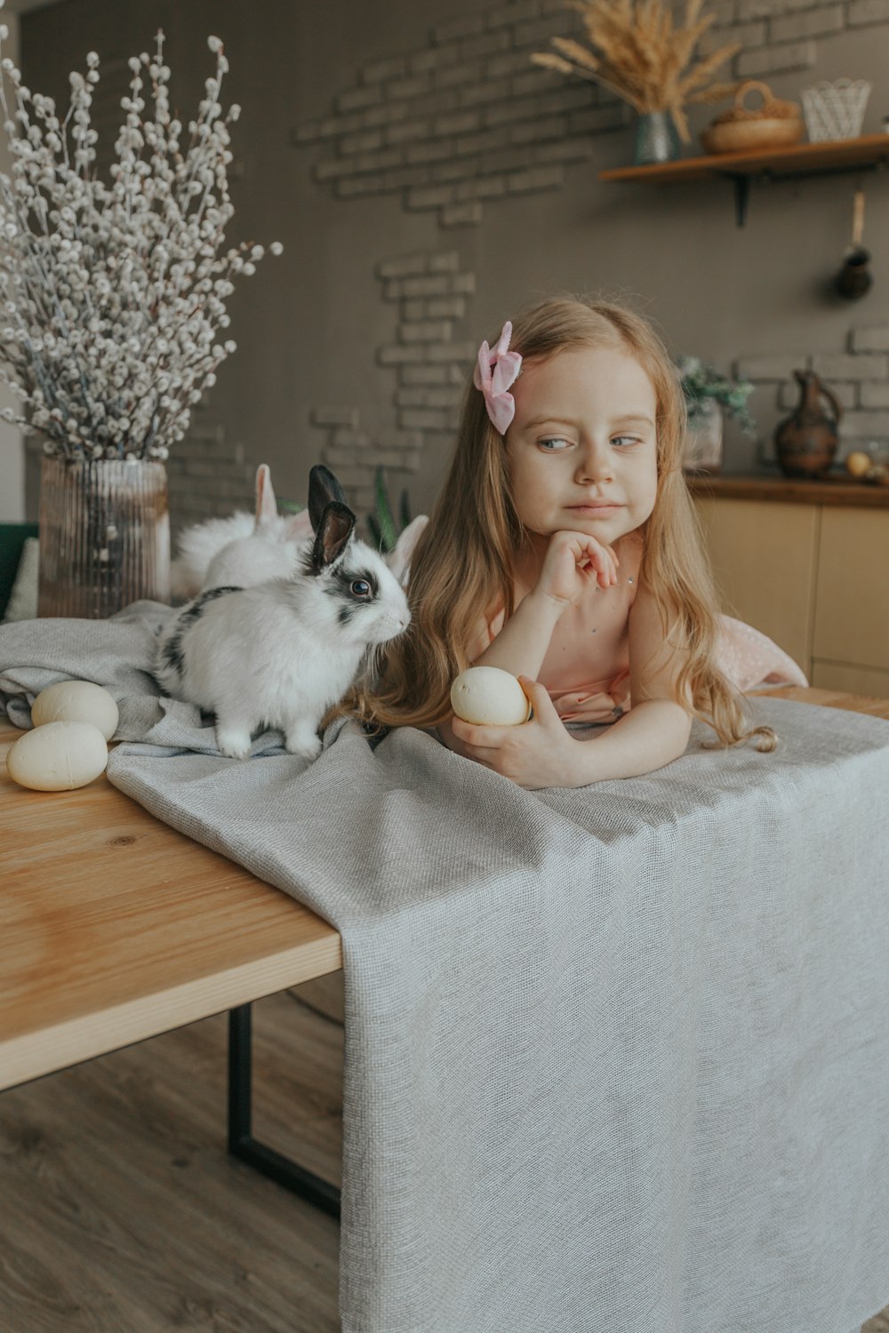 girl in white dress sitting on brown wooden table with white and black cat