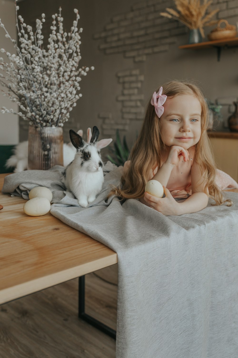 girl in white sweater sitting beside white and black cat on brown wooden table