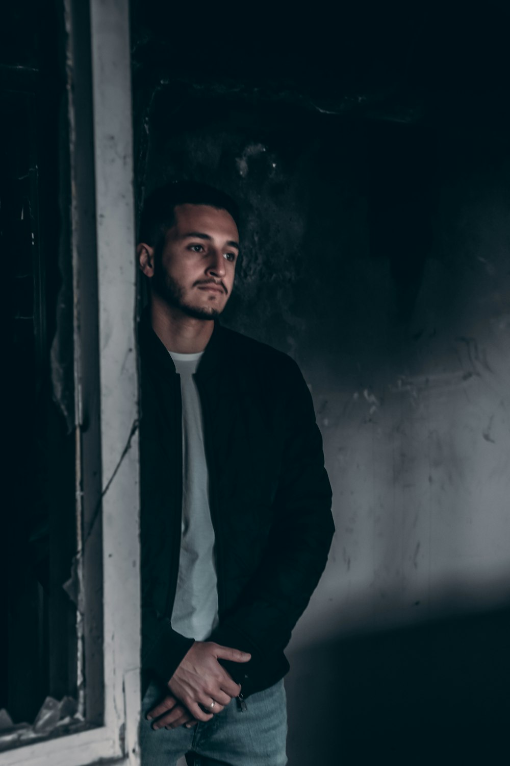 man in black suit jacket standing beside white wall