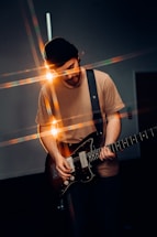 man in white crew neck t-shirt playing electric guitar