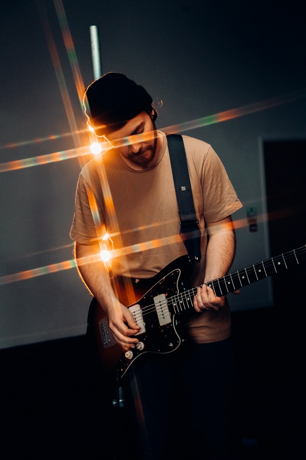 Hombre con camiseta blanca de cuello redondo tocando la guitarra eléctrica