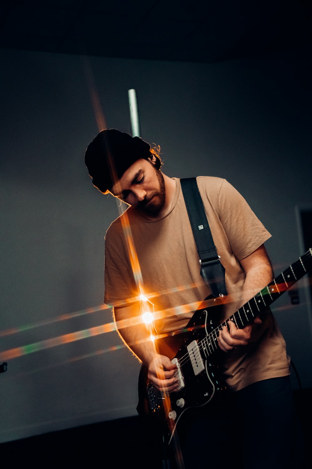 Hombre con camiseta blanca de cuello redondo tocando la guitarra eléctrica