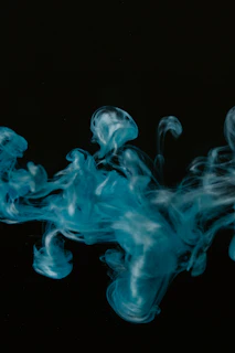 A dynamic shot of a preroll releasing a gentle, colorful smoke that blends into a cosmic swirl of blues and reds