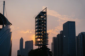 A sleek architectural blueprint overlaying a modern skyscraper under construction at sunset.