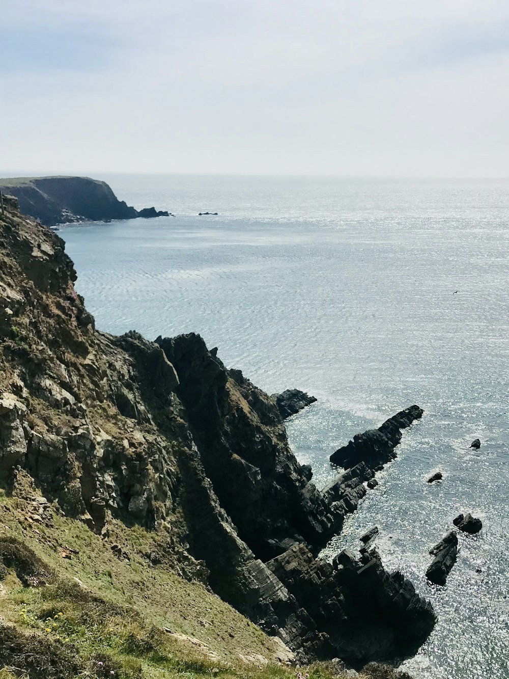 montagne brune et verte au bord de la mer pendant la journée