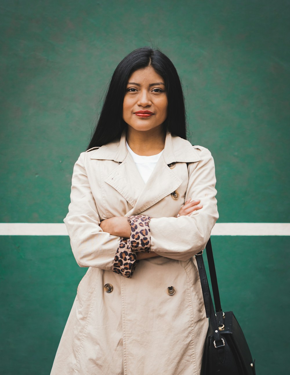 woman in beige coat standing near green wall