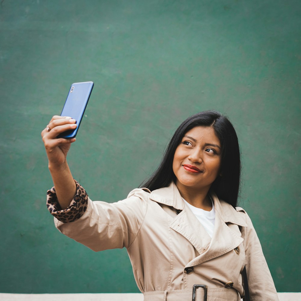 woman in brown coat holding white tablet computer